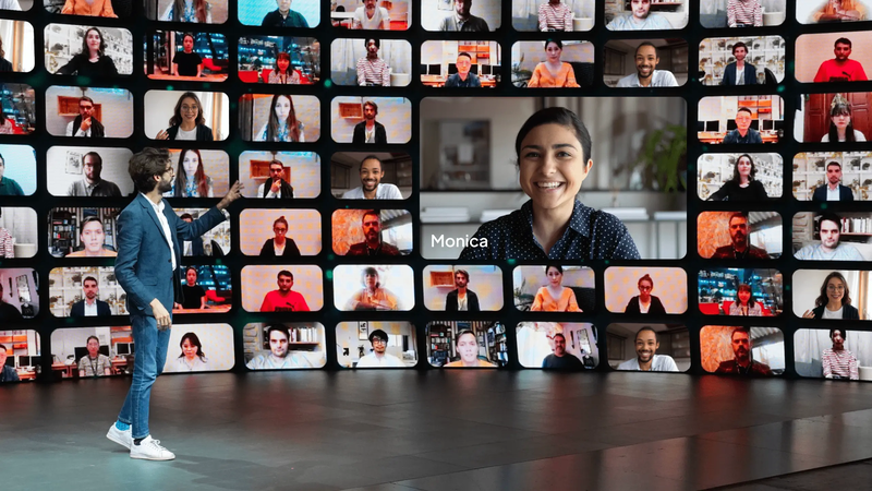 Image illustre un intervenant sur scène qui interagit avec une participante à distance connectée dans une mosaïque vidéo